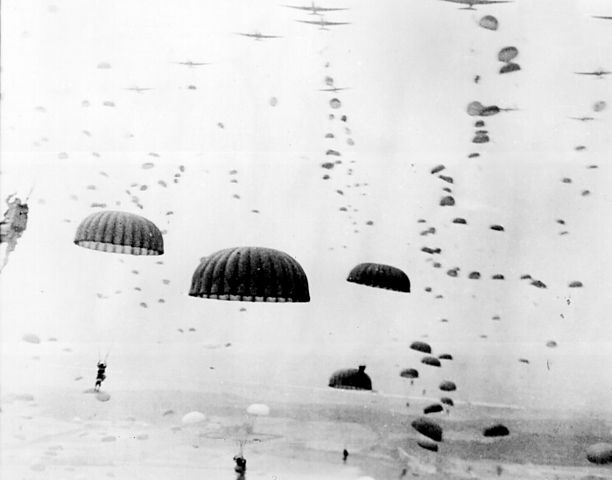 Parachutes open overhead as waves of paratroops land in Holland during operations by the 1st Allied Airborne Army.
